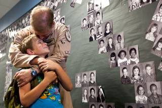 Aaron Powell, 9, receives a kiss from his dad in the school hallway after he surprised him by coming home early from serving in Afghanistan at Henry and Evelyn Bozarth Elementary School Thursday, May 23, 2013.